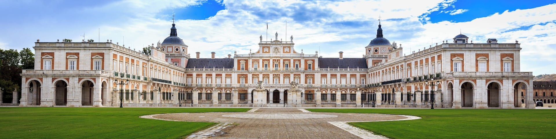 A grand palace with symmetrical architecture, a central courtyard, and a clear sky.