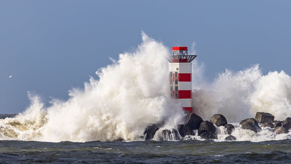 Un phare aux rayures rouges et blanches, entouré de vagues déferlantes.