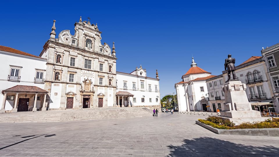 A historic square with a prominent church featuring ornate architecture and a statue.