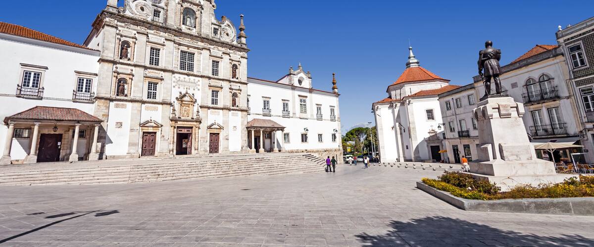 A historic square with a prominent church featuring ornate architecture and a statue.