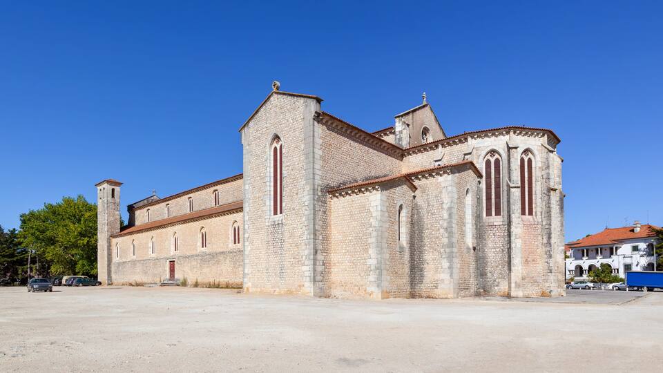 A historic stone church with a bell tower and arched windows.