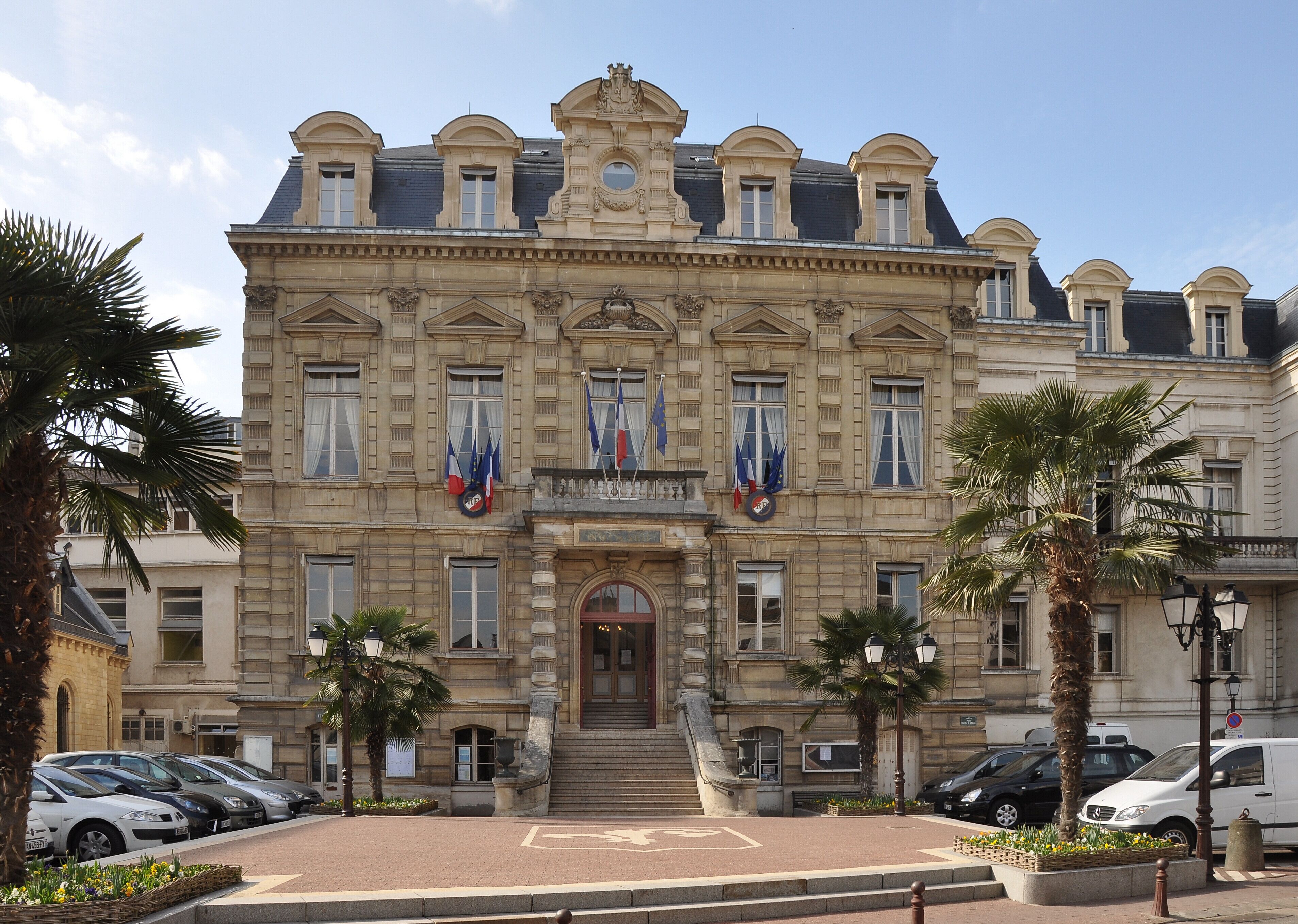A historic building with classical architecture, featuring a central entrance, multiple windows, and flags.