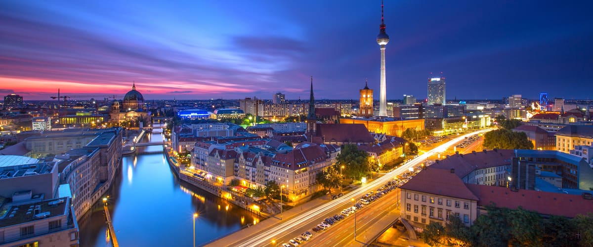 A cityscape at dusk with a prominent tower, a river, and illuminated buildings.