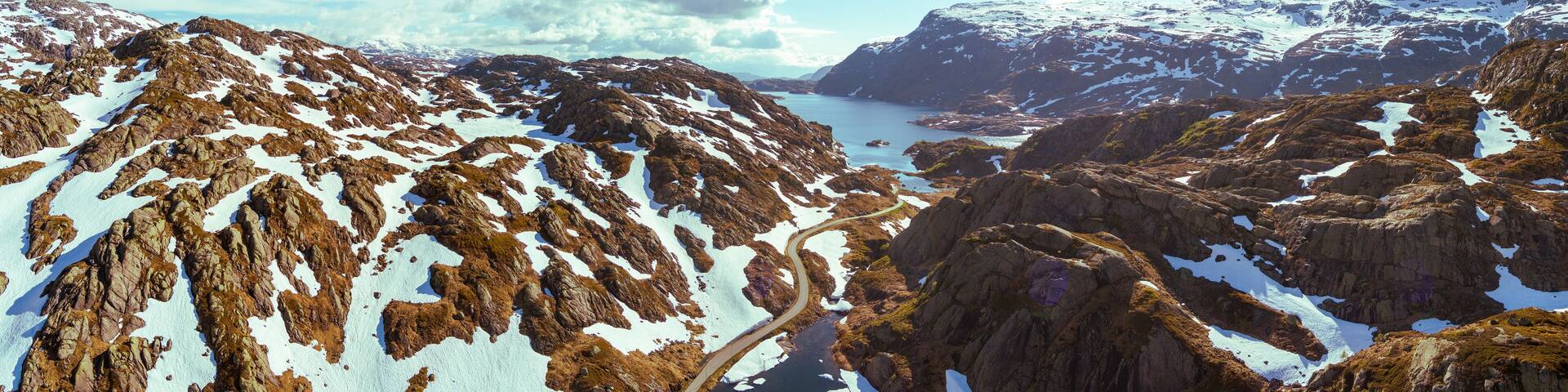 Mountain landscape in summer. Aerial view at glacier melted lake, mountains ridge, and highway. Nature park in Sauda municipality, Rogaland fylke. Beautiful nature of Norway. Horizontal banner
