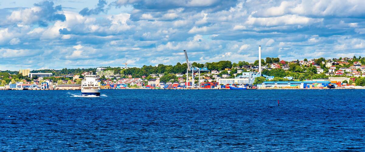 A coastal city with a large body of water, a ship, and industrial cranes.
