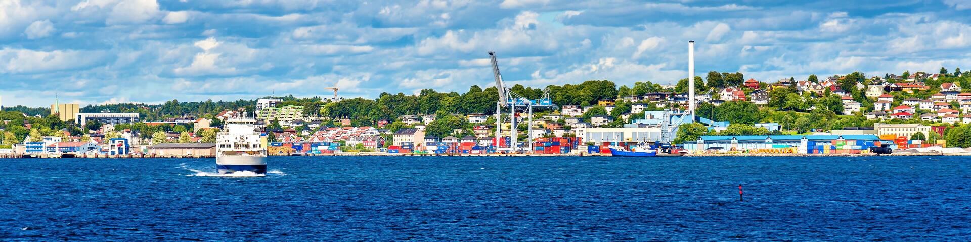 A coastal city with a large body of water, a ship, and industrial cranes.