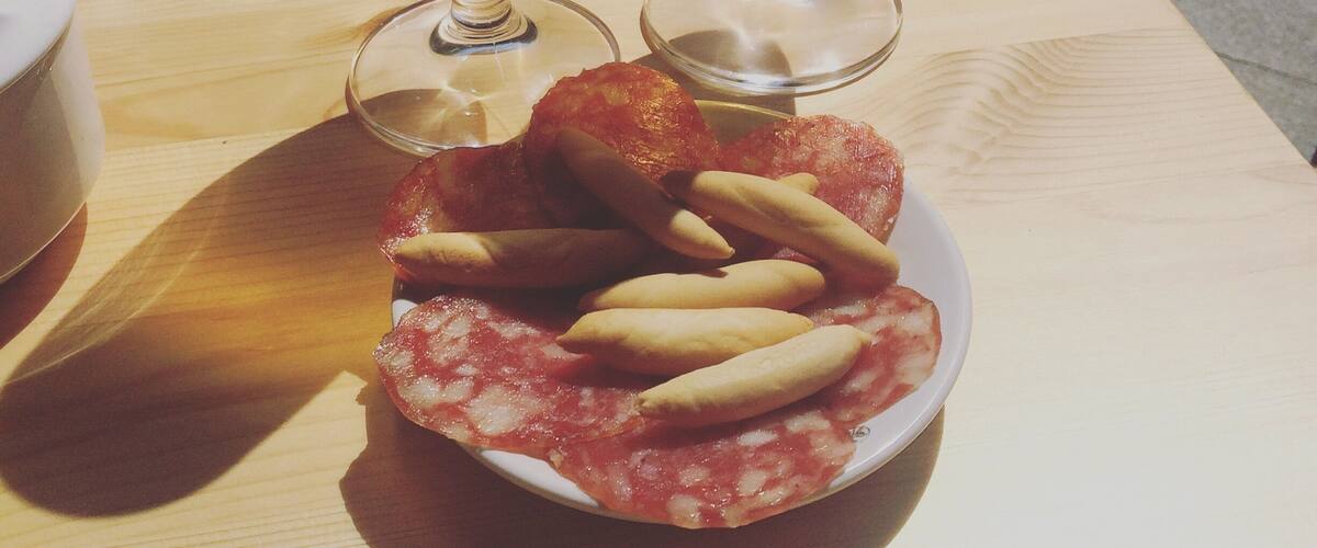 Two glasses of beer with a plate of food in the foreground.
