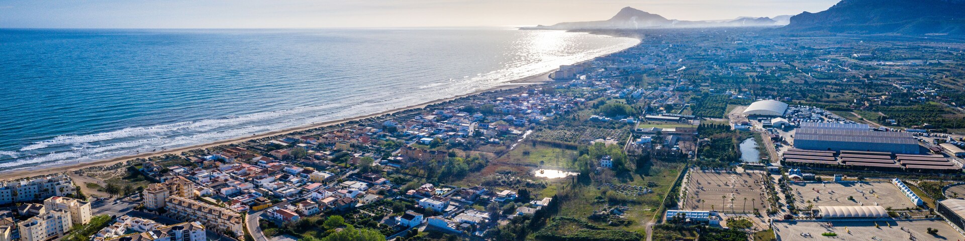 A coastal cityscape with a beach, residential areas, and a stadium.