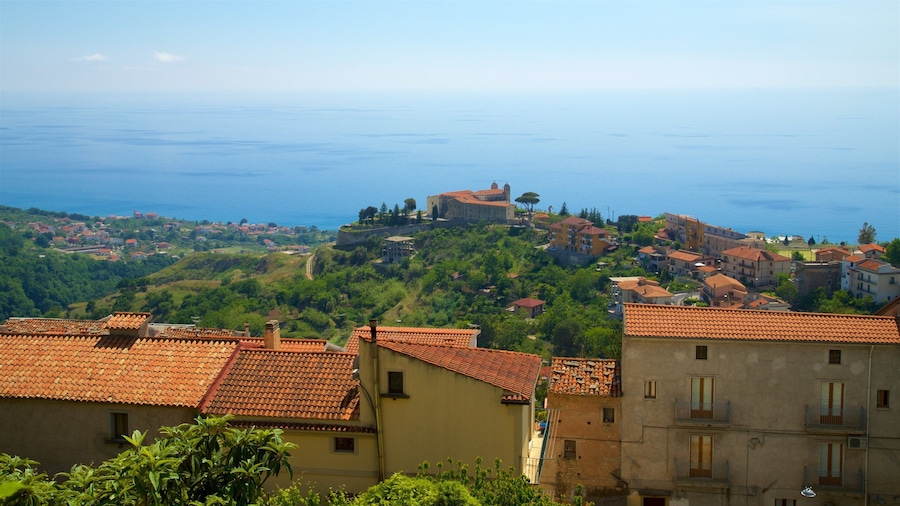 A coastal town with terracotta-roofed buildings, a prominent castle on a hill, and the sea in the background.