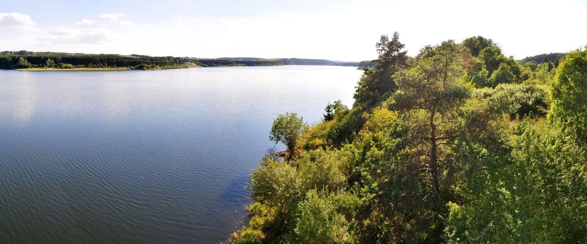 A calm lake surrounded by dense forests and hills.