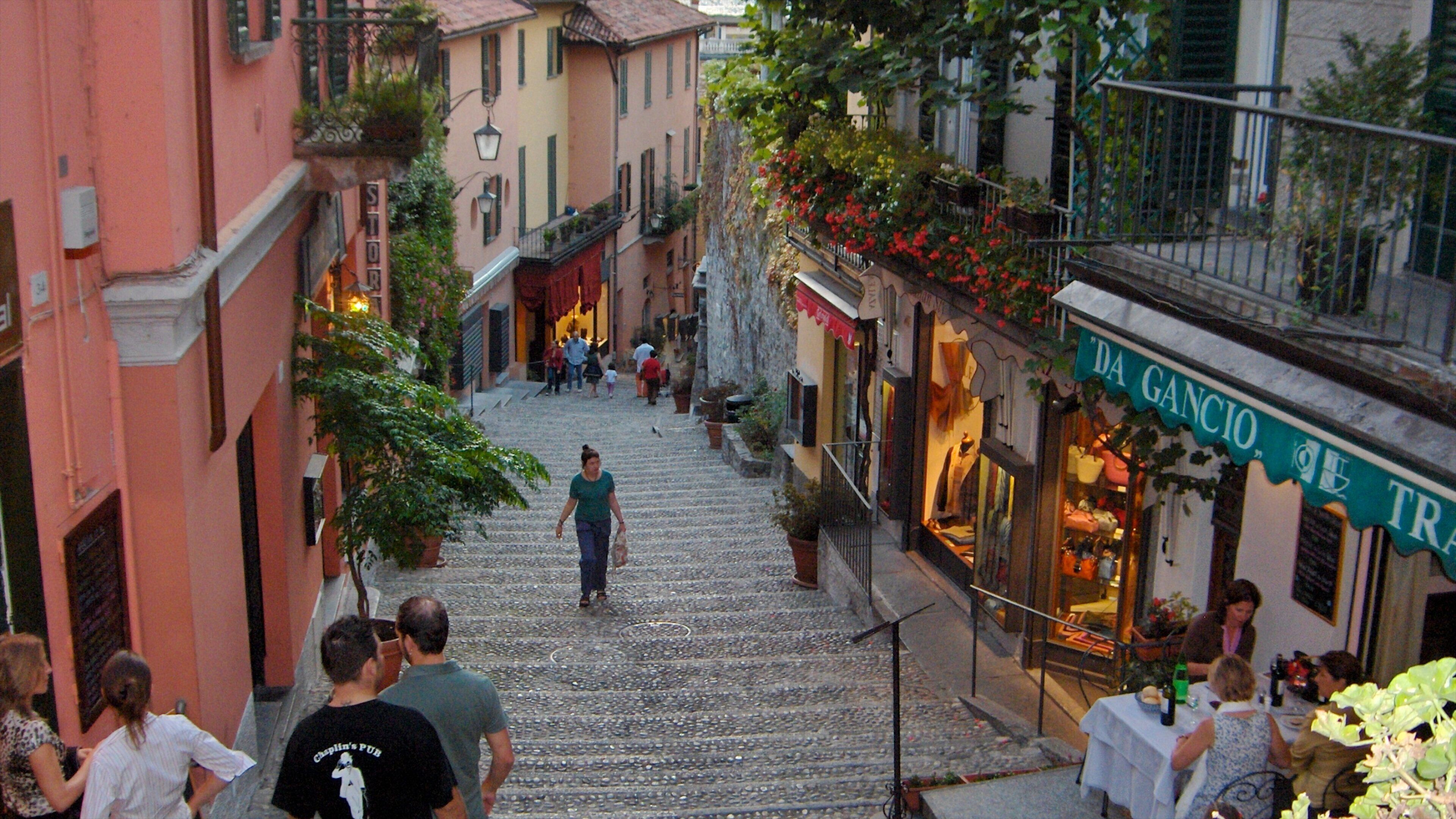 A cobblestone street in a European town with shops and people walking.