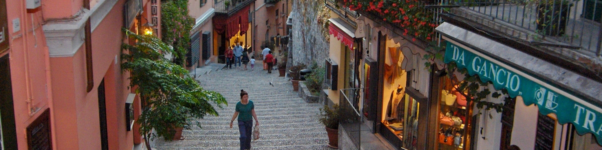 A cobblestone street in a European town with shops and people walking.