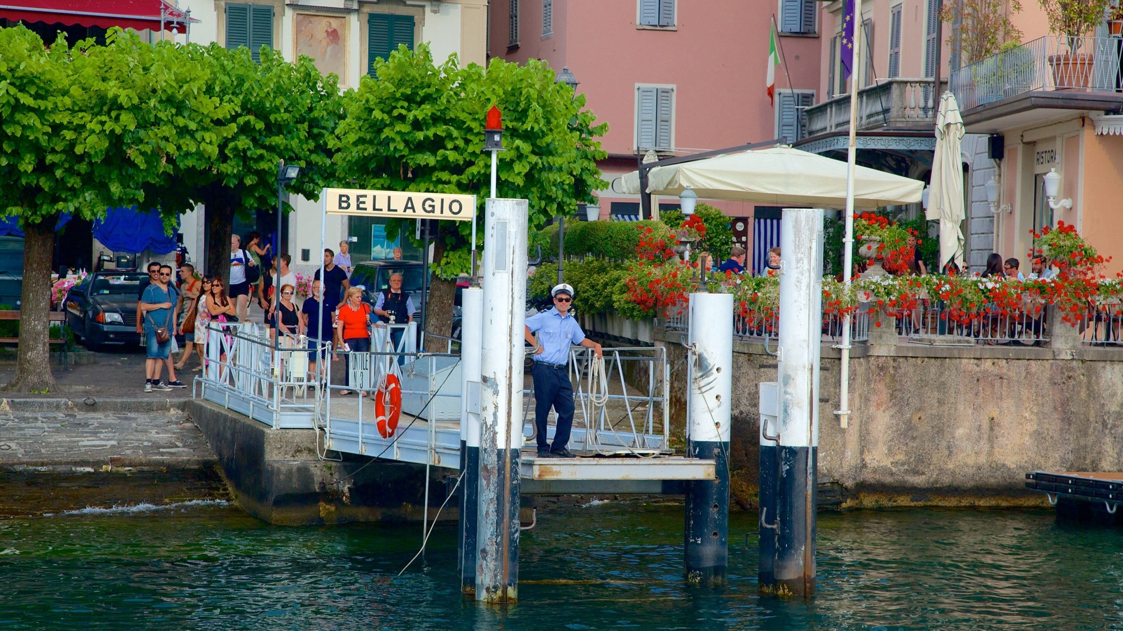 Un muelle con un flotador salvavidas, un cartel que dice "BELLAGIO" y una persona con uniforme.