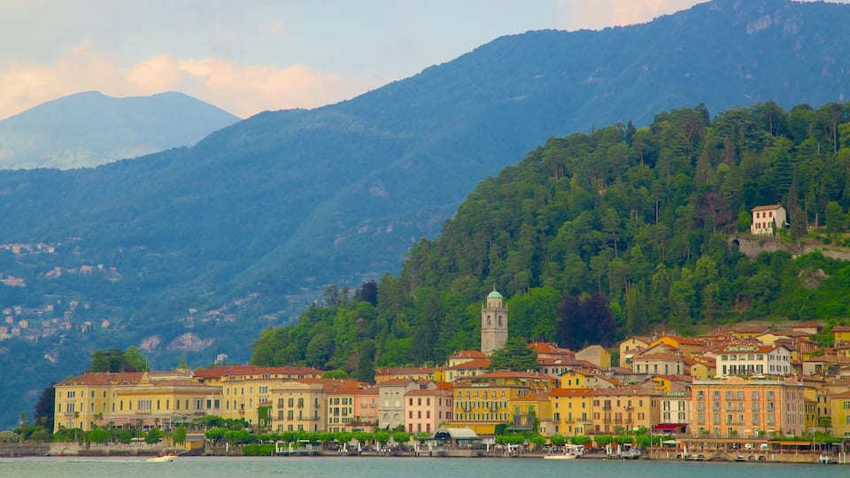 A coastal town with colorful buildings, a prominent tower, and a backdrop of mountains.