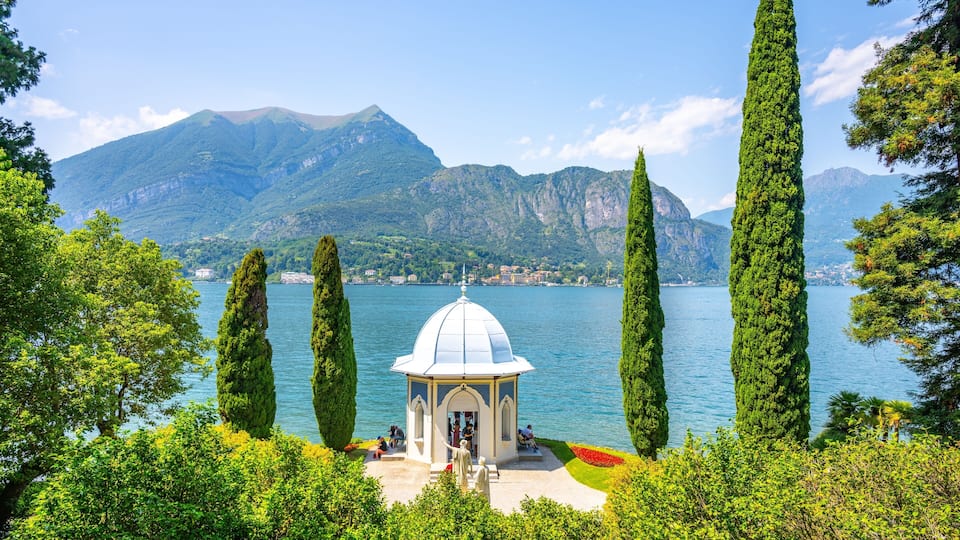 A gazebo by a lake with mountains in the background.