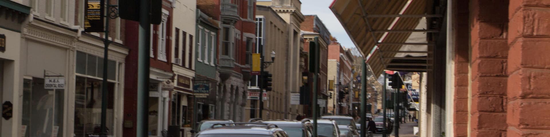 A street lined with historic buildings, including a red brick tower and a white building with arched windows.