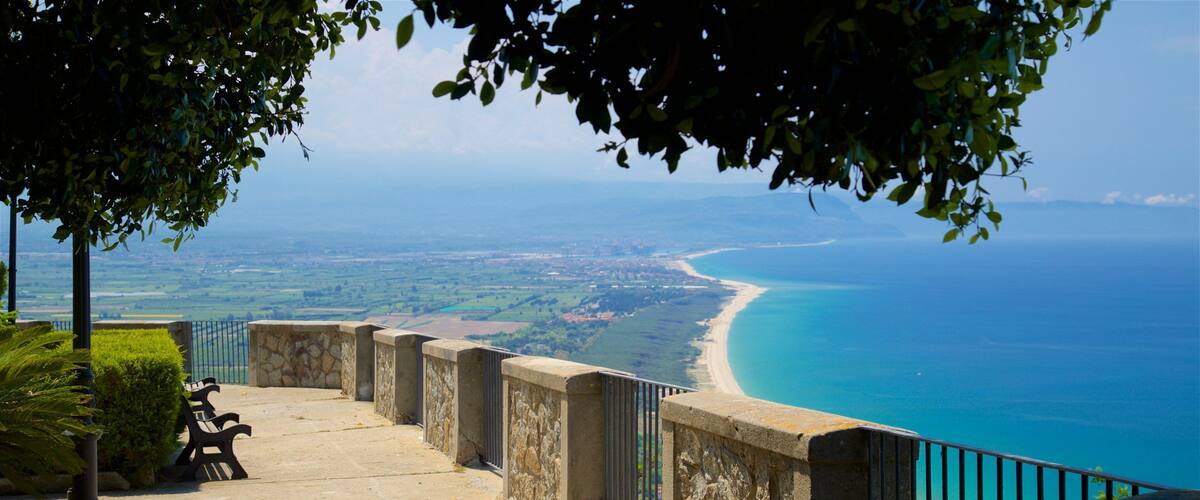 A coastal walkway with benches overlooking a beach and the ocean.