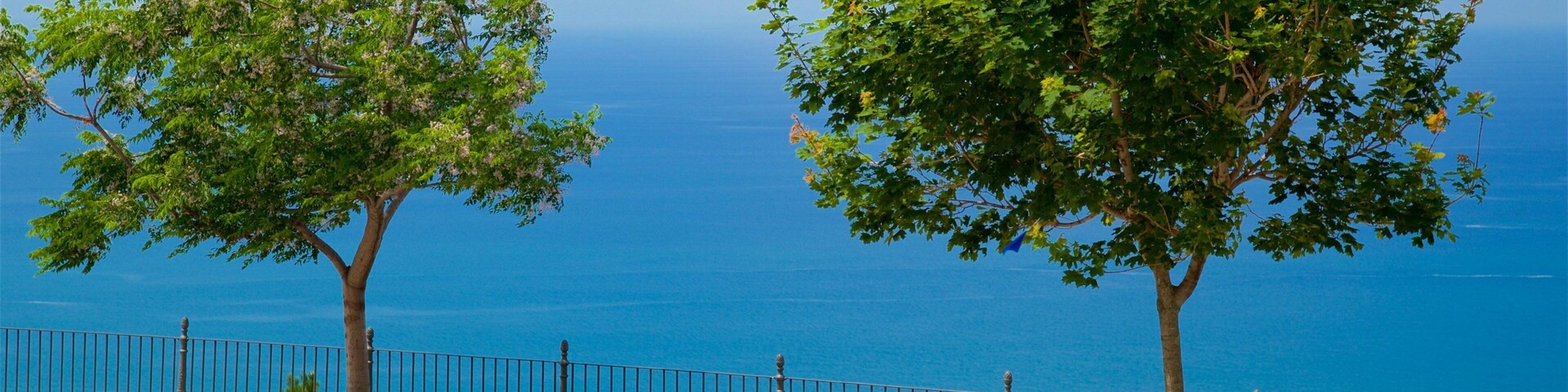 Un banco junto a una barandilla azul con vistas a un cuerpo de agua.