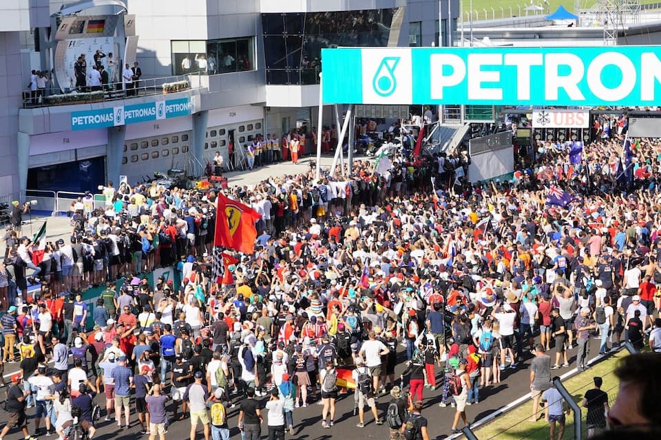 A large crowd at a sporting event with a prominent PETRONAS sign.