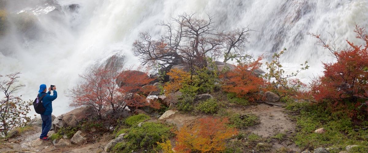 A waterfall with a person taking a photo.