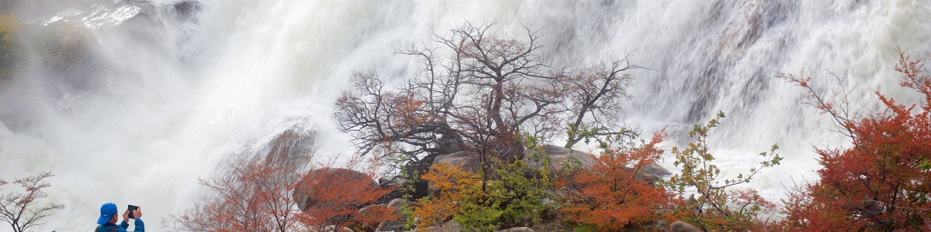 A waterfall with a person taking a photo.