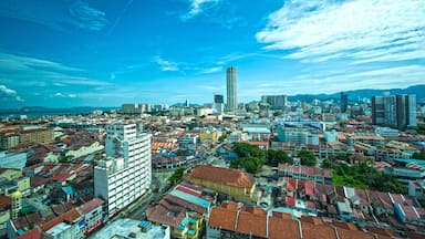 A coastal cityscape with a prominent tall building, dense urban architecture, and a clear blue sky.