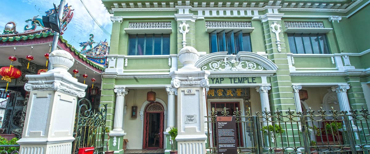 A traditional temple with ornate architecture, a sign reading "Yap Temple," and a gate with a plaque.