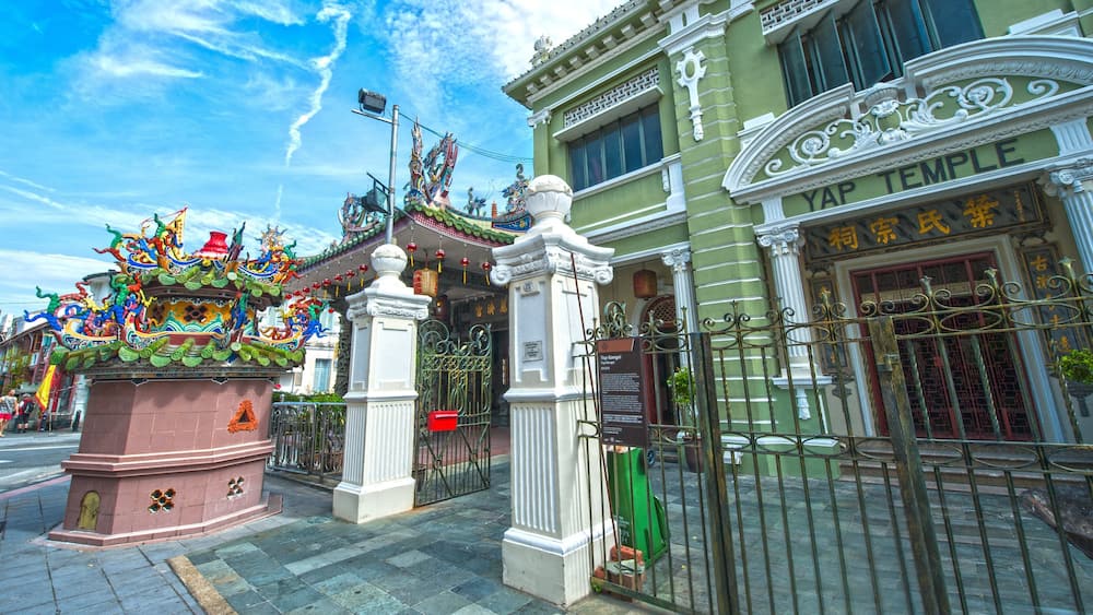 Un temple à l’architecture chinoise richement décorée, une sculpture colorée de dragon et une enseigne indiquant « TEMPLE YAP ».