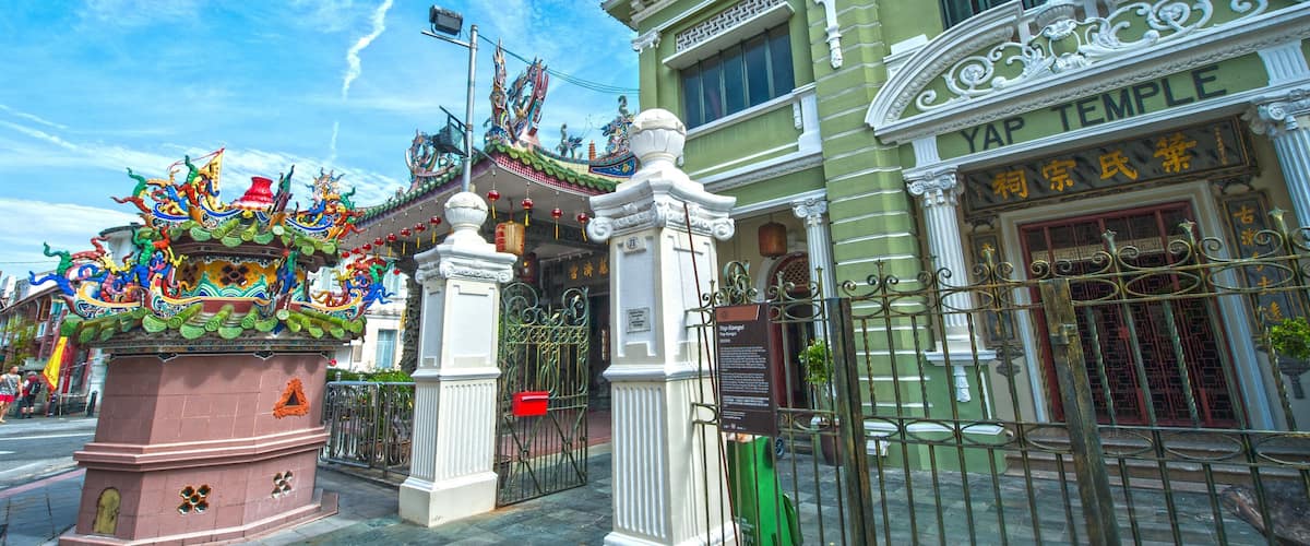 A temple with ornate Chinese architecture, a colorful dragon sculpture, and a sign reading "YAP TEMPLE".