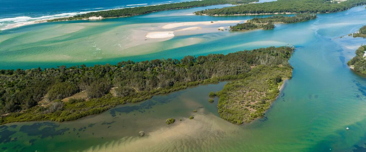 A coastal landscape with clear blue waters, sandy beaches, and dense green forests.