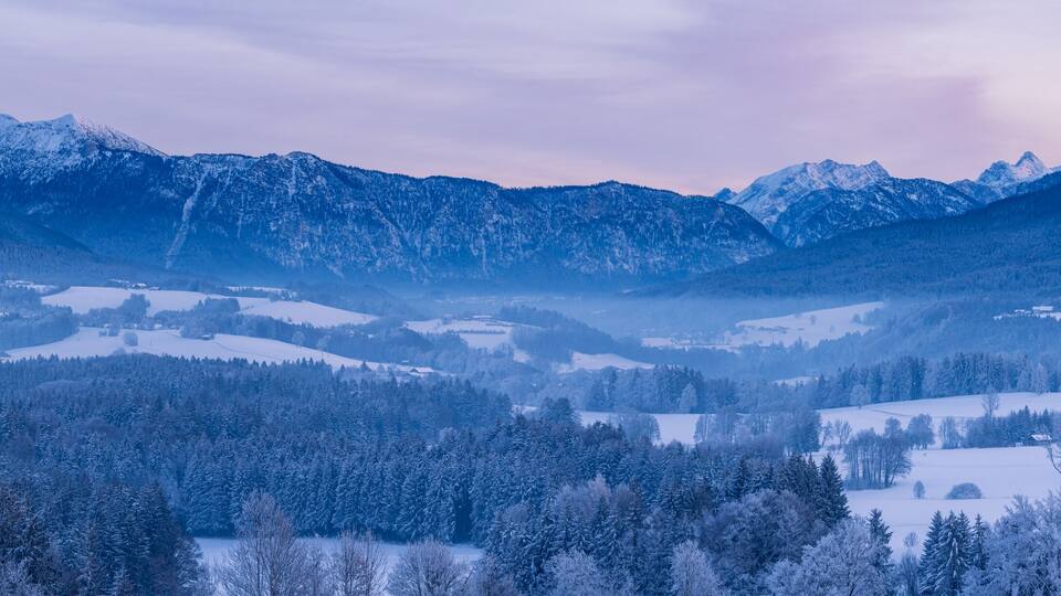 A snow-covered mountain range with a valley in the foreground.