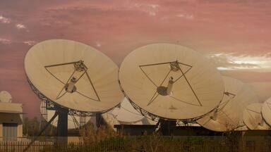 Antenas parabólicas grandes bajo un cielo rosado.