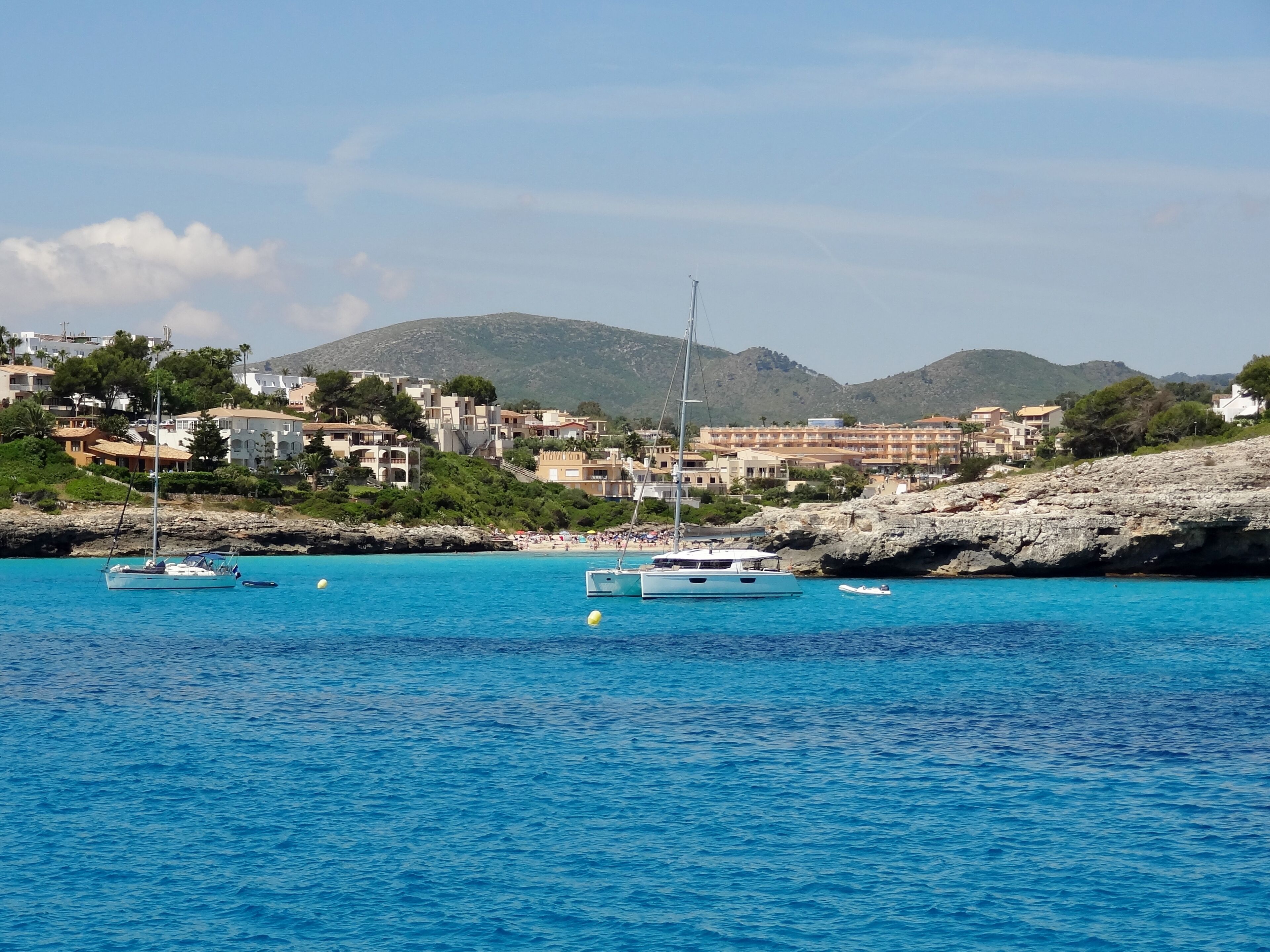 A coastal town with buildings, boats, and a mountainous background.