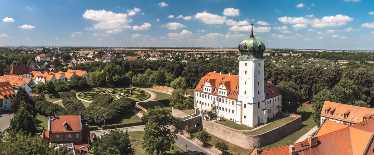A historic town with a prominent tower, a circular garden, and surrounding residential buildings.