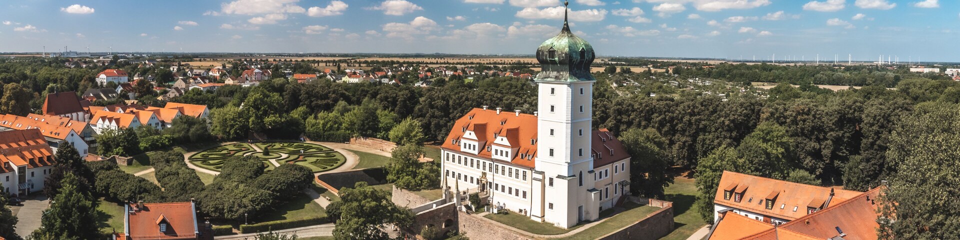 A historic town with a prominent tower, a circular garden, and surrounding residential buildings.