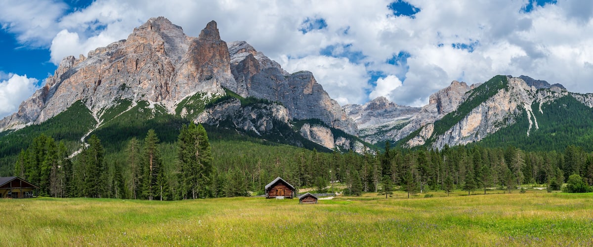 A mountain landscape with a cabin and a field.