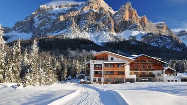 A snow-covered mountain range with a wooden chalet in the foreground.