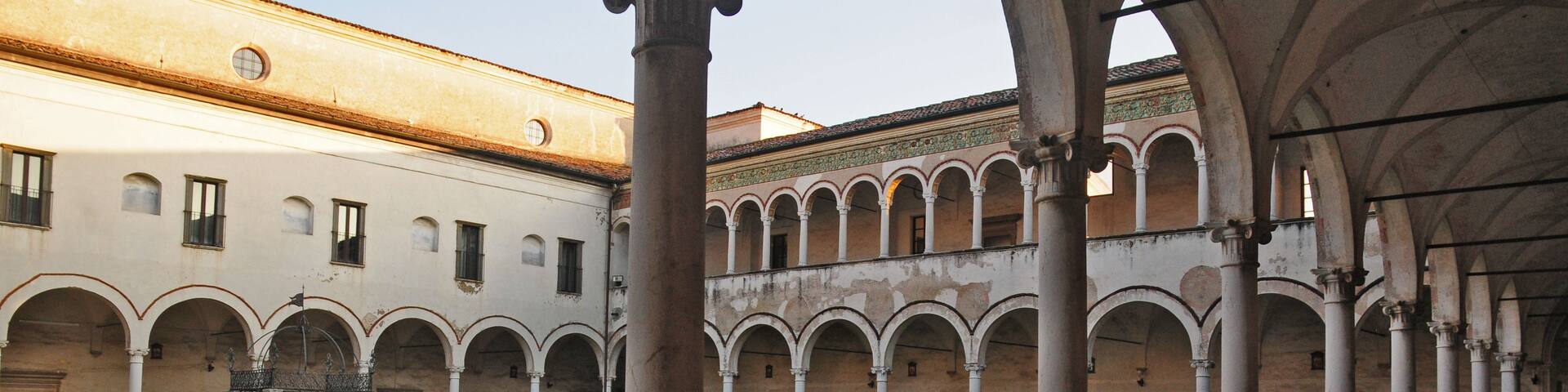 An ancient cloister with a central courtyard, surrounded by arched walkways and columns.