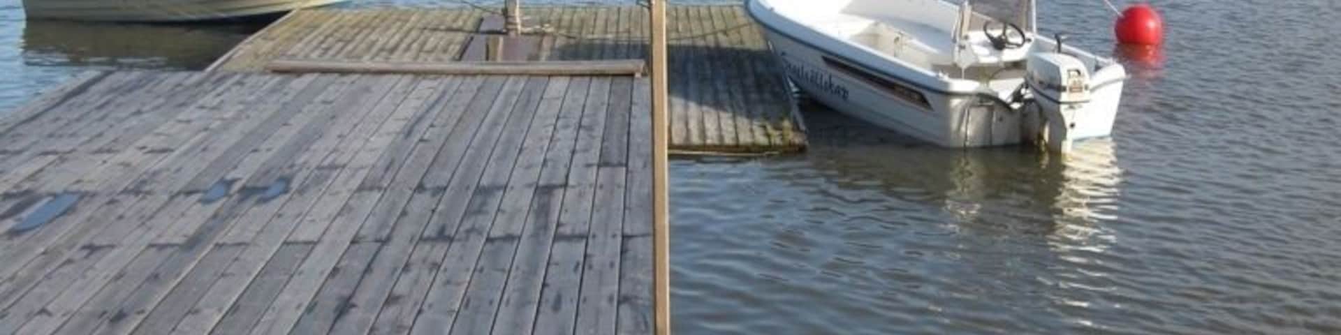 A wooden dock with a small boat named "Uttern" docked at the pier.