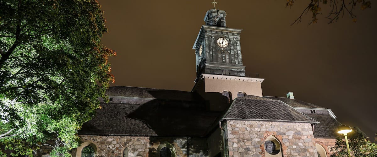A stone church with a clock tower at night.