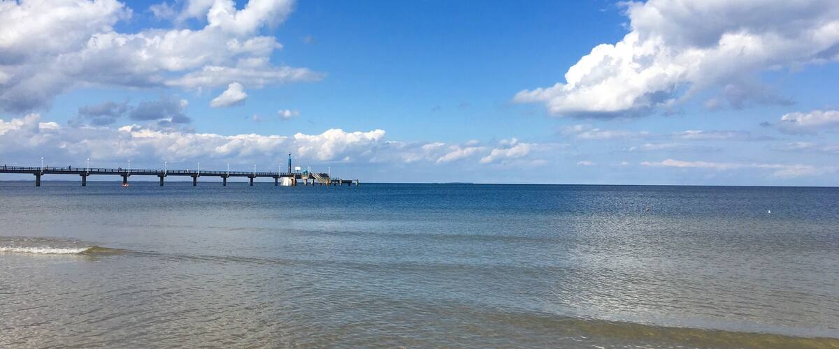 A pier extending into calm waters under a clear sky.