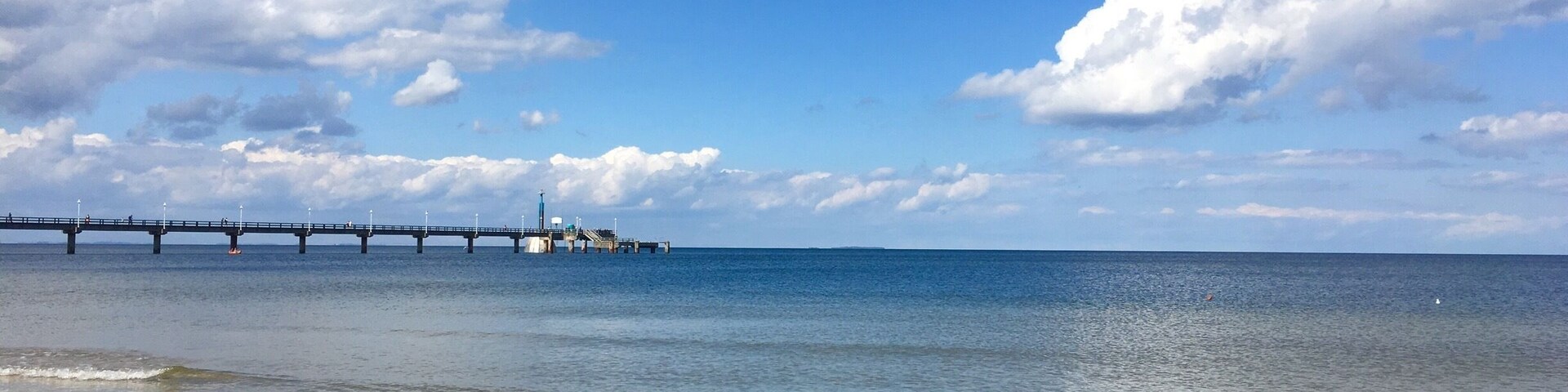 A pier extending into calm waters under a clear sky.
