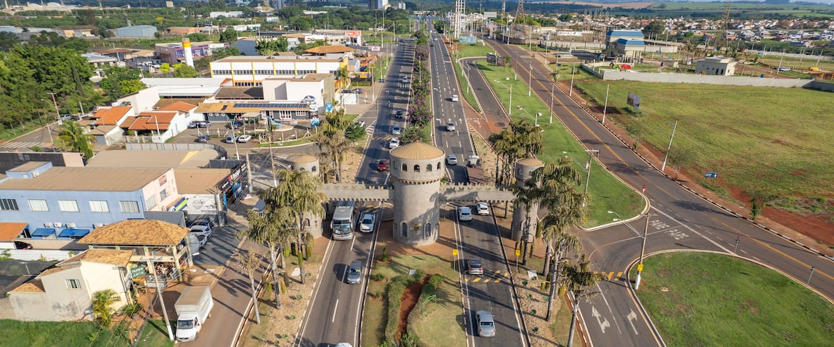 A cityscape with a prominent round tower, intersecting roads, and surrounding greenery.
