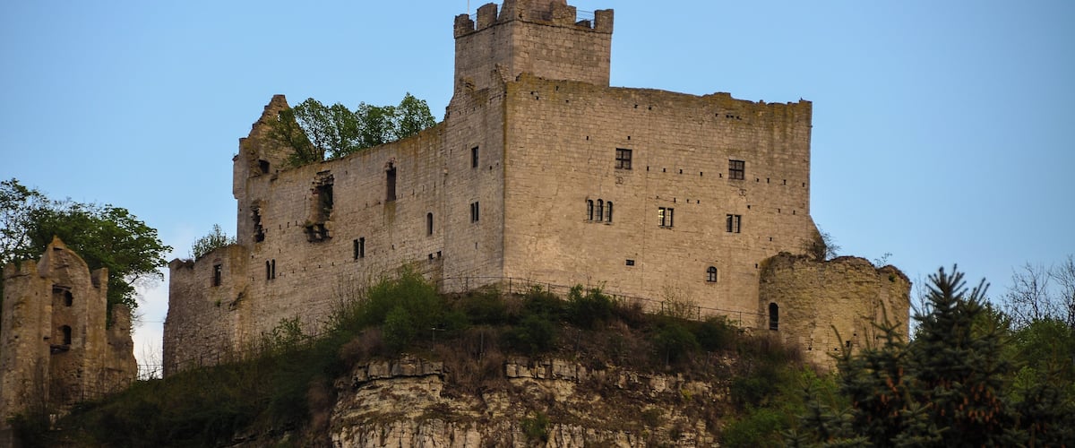 A large, historic stone castle on a cliff with a clear sky.