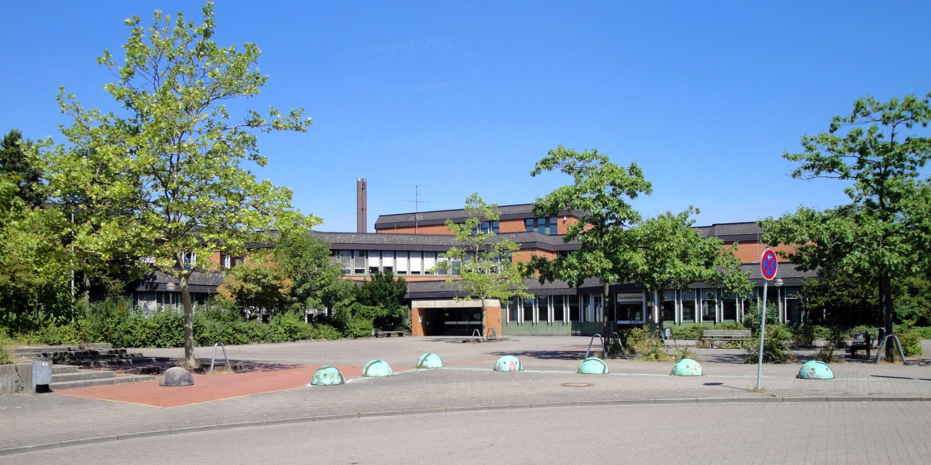 A courtyard with trees, a building, and a no parking sign.