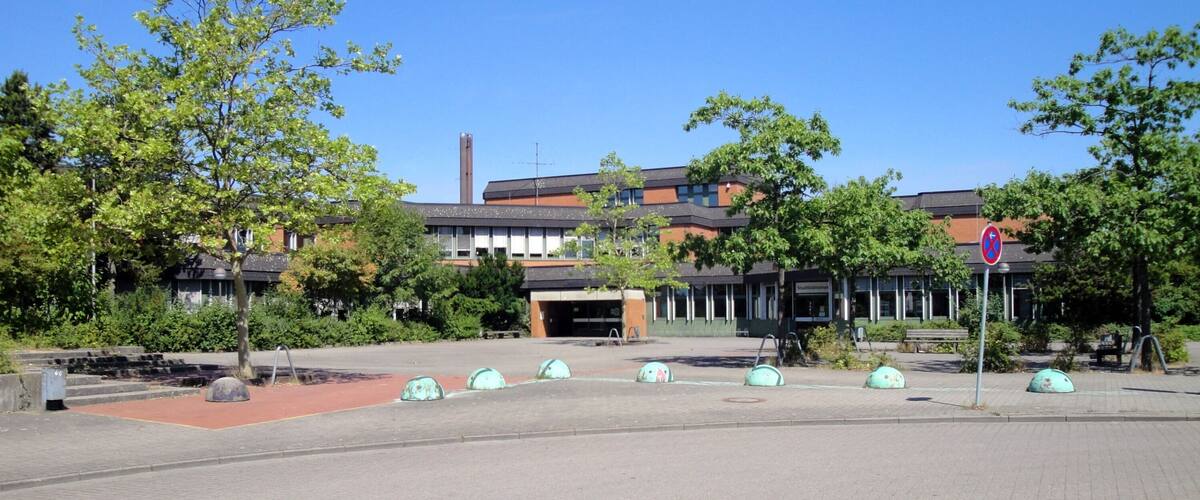 A courtyard with trees, a building, and a no parking sign.