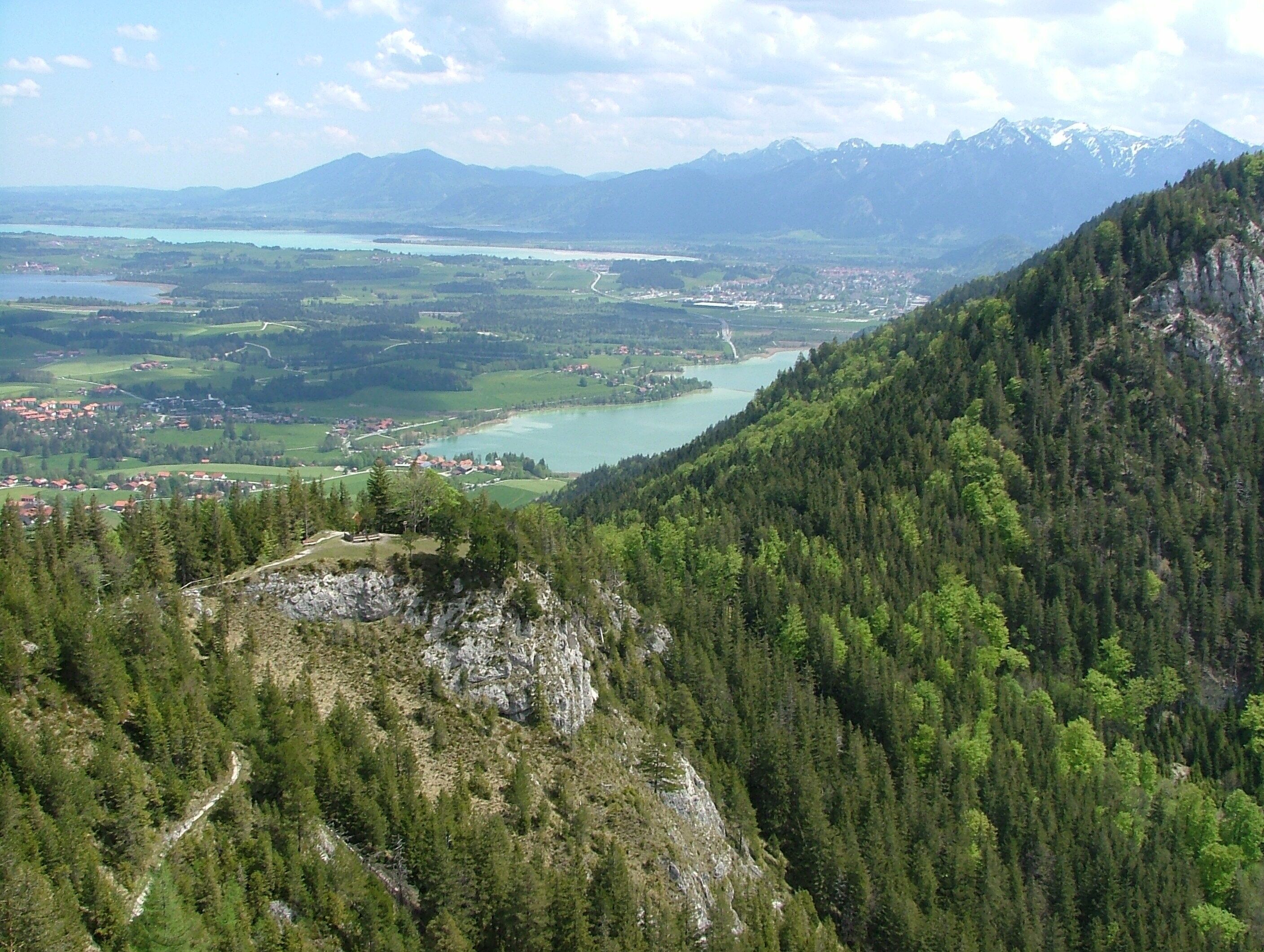 A mountainous landscape with a river, a town, and a lake.