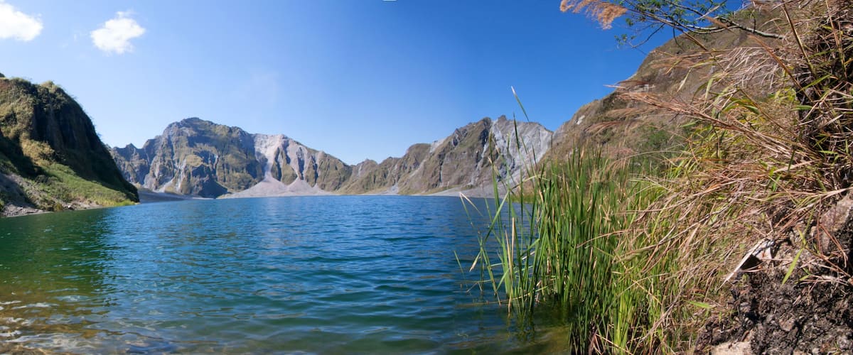A clear lake surrounded by rocky mountains and dense greenery.