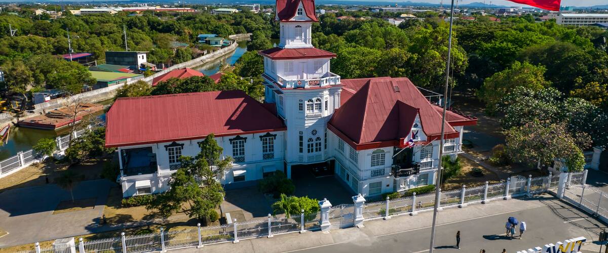 A white building with a red roof, a tower, and a flagpole with a flag.