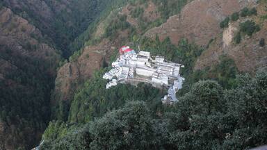 Un paisaje montañoso con un conjunto de edificios en una ladera empinada.